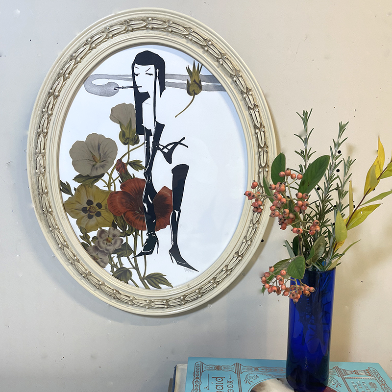 Handmade art combining screen printing and a collage of flowers depicting a woman pulling up her stocking while smoking in a upcycled white oval frame